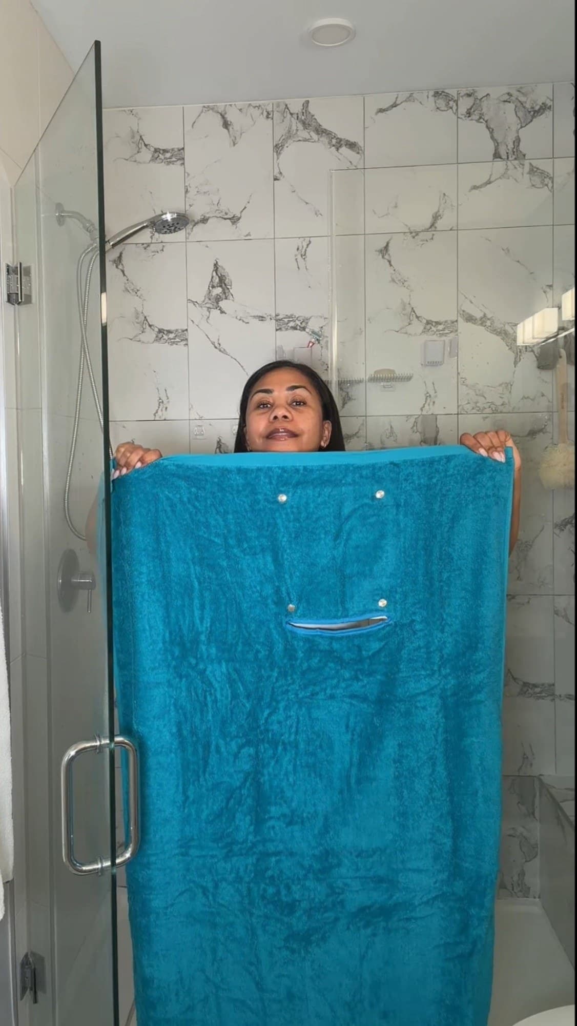 A woman holding up the Smart Towel in Capri Breeze, showing the snap-on pocket.